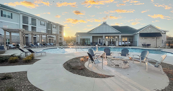 Apartment complex and clubhouse with pool at sunset